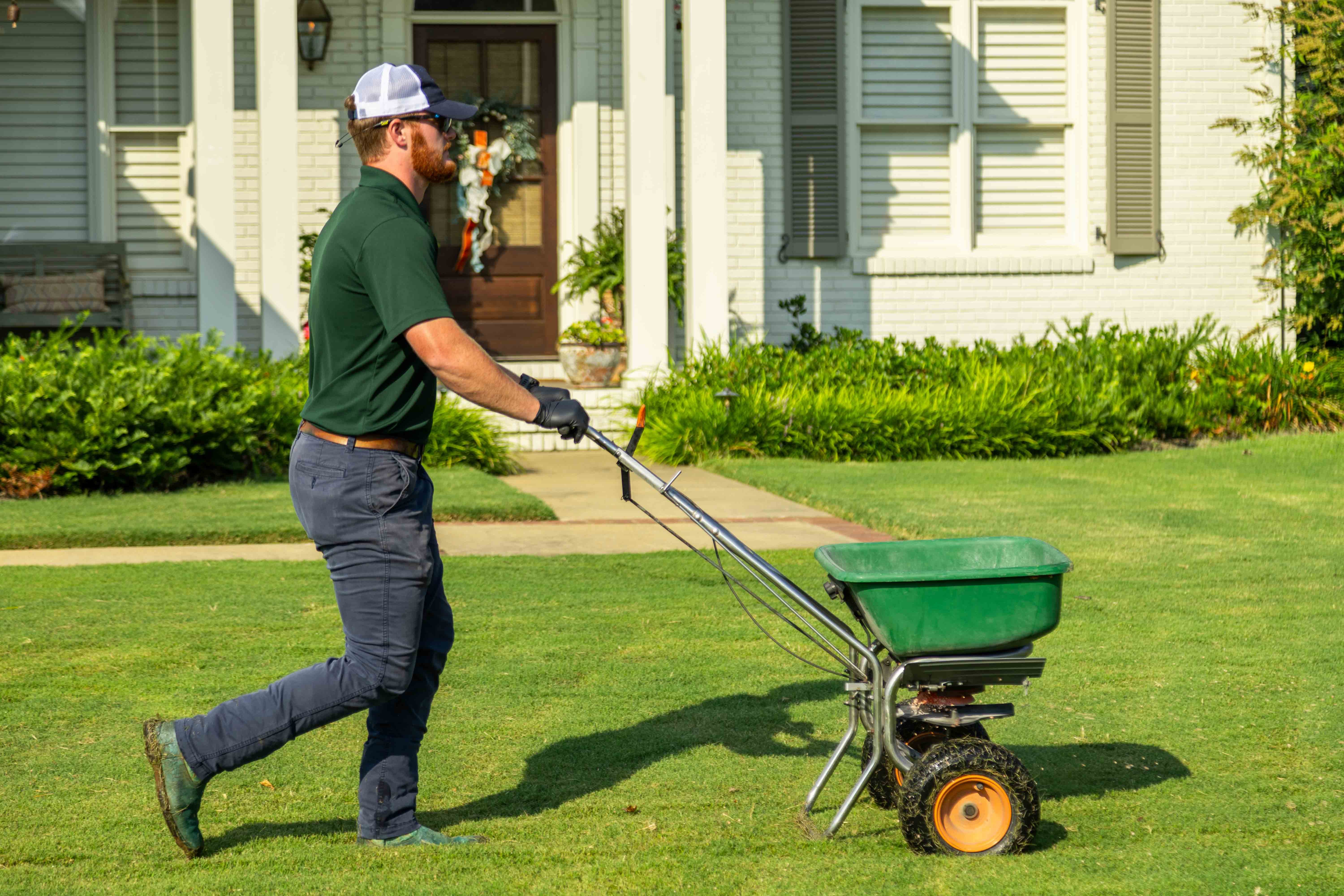 lawn care technician spreading granular fertilizer on a lawn