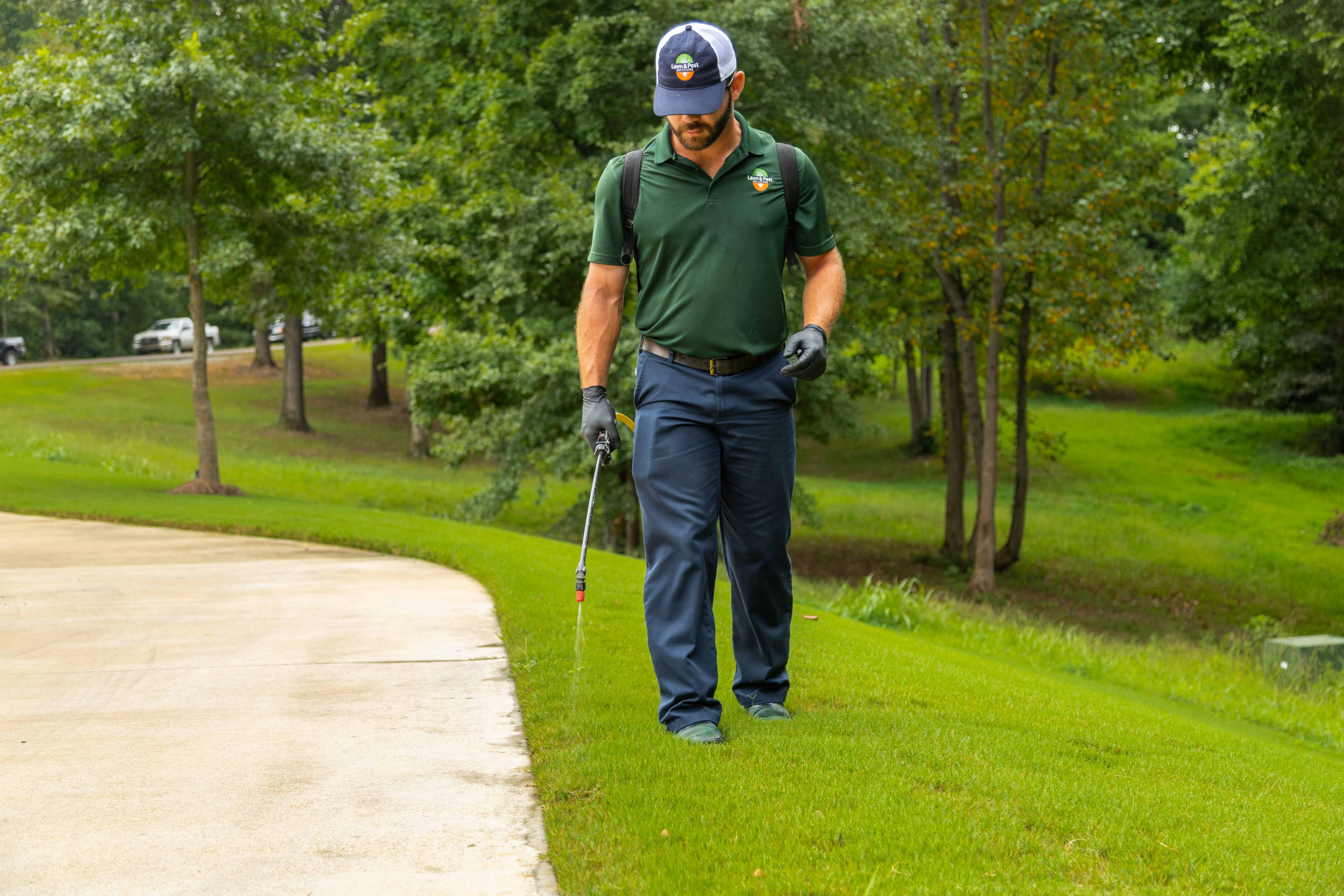 lawn care technician spraying grass weeds treatment crew