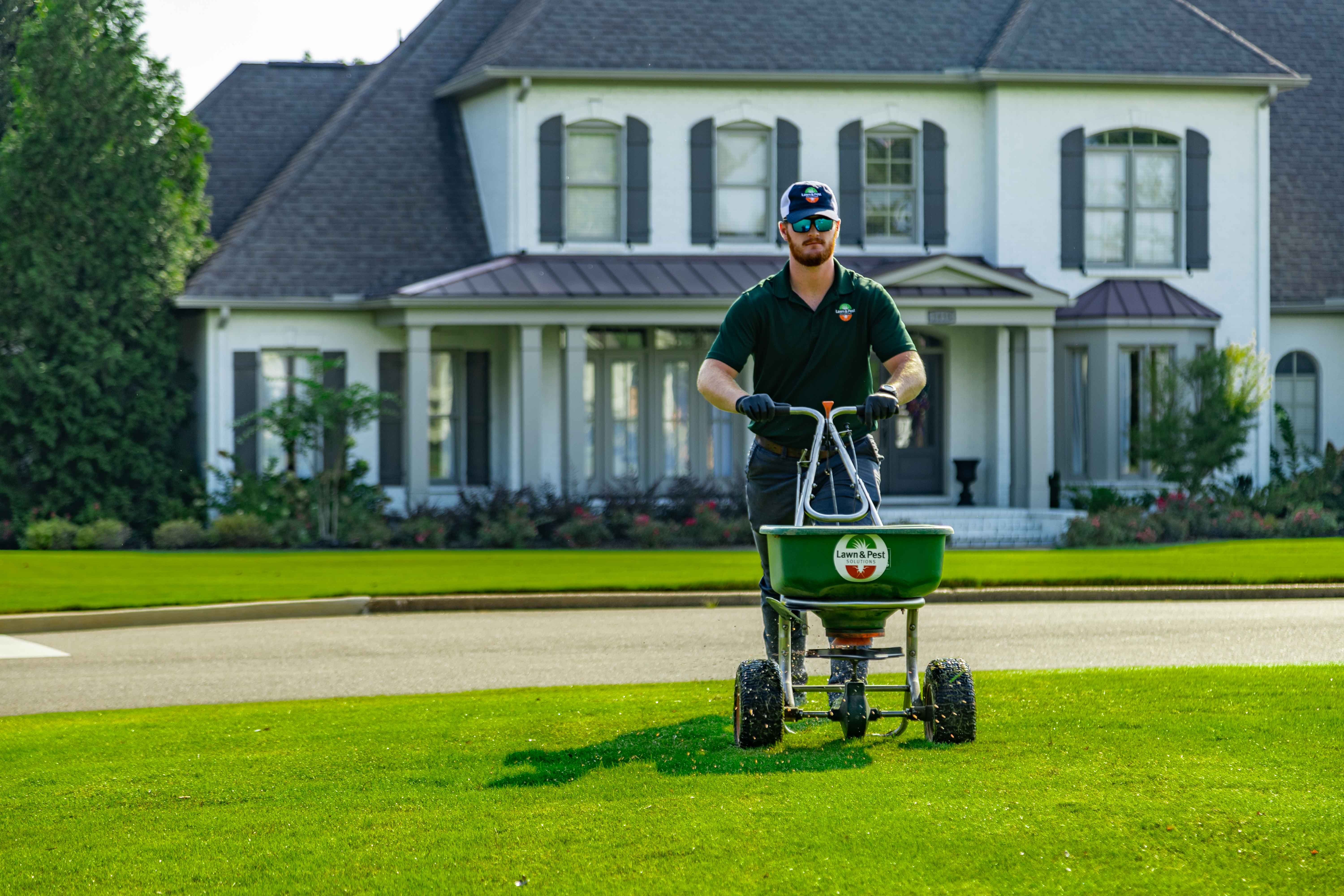 lawn care technician spreading granular fertilizer on a nice memphis lawn