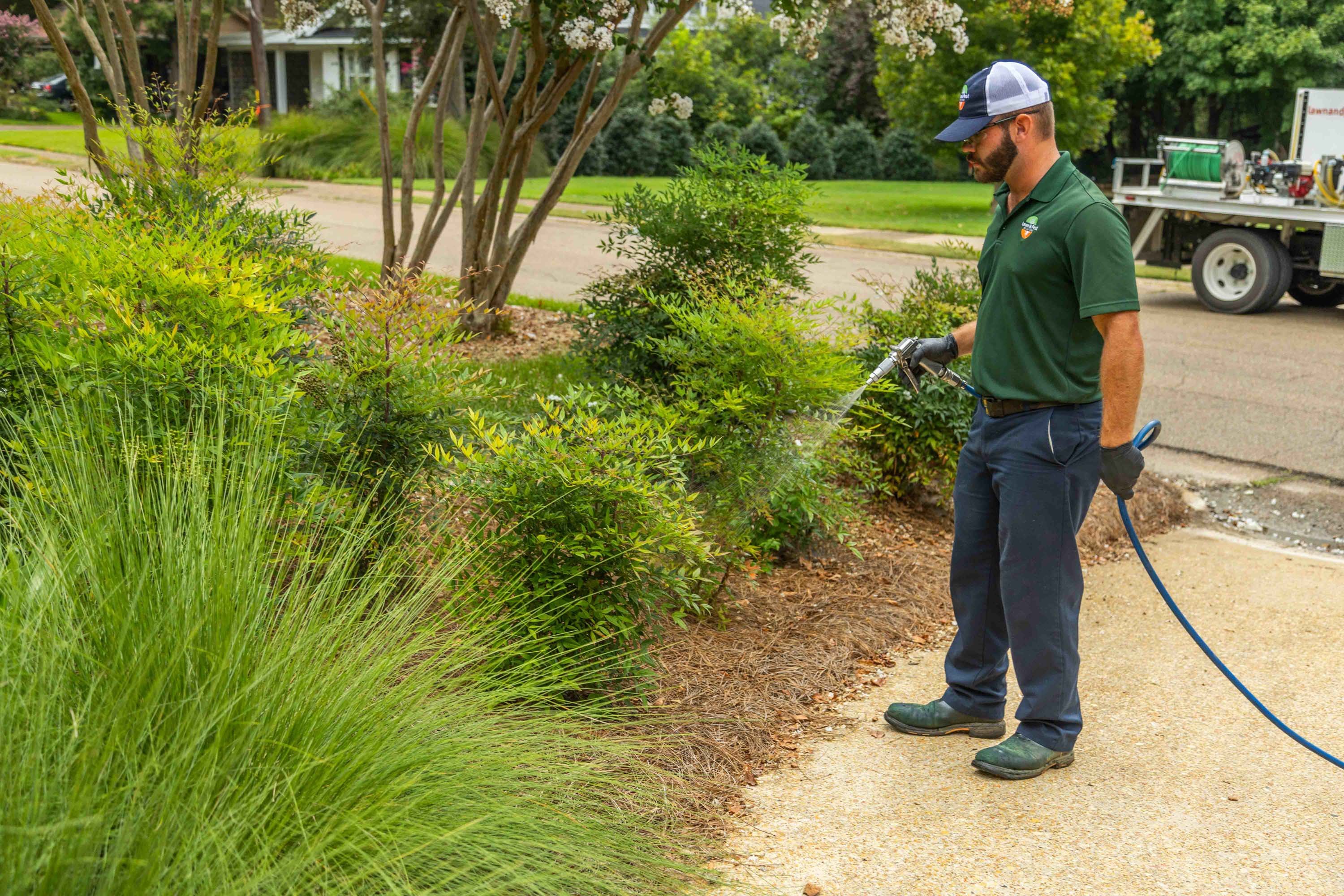 plant health care technician spraying a planting bed