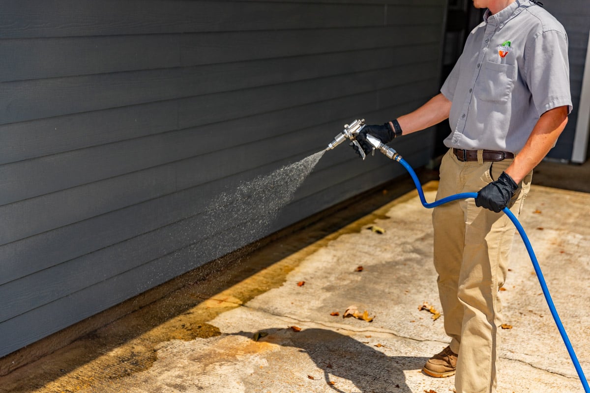 pest control technician spraying the foundation of a house