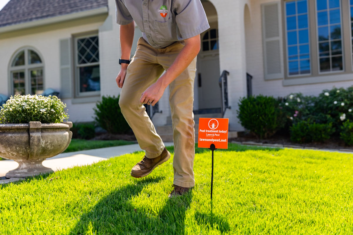 pest control technician placing yard sign in lawn 2